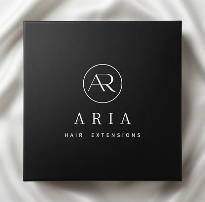 Black ARIA HAIR hair extension packaging on light fabric